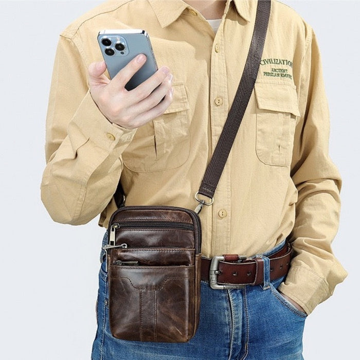 Man carrying the TC2014 leather waist bag crossbody while using his phone - Touch and Catch NZ